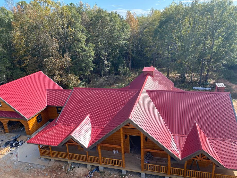 Aerial view of a rustic lodge with bright red roofs surrounded by trees