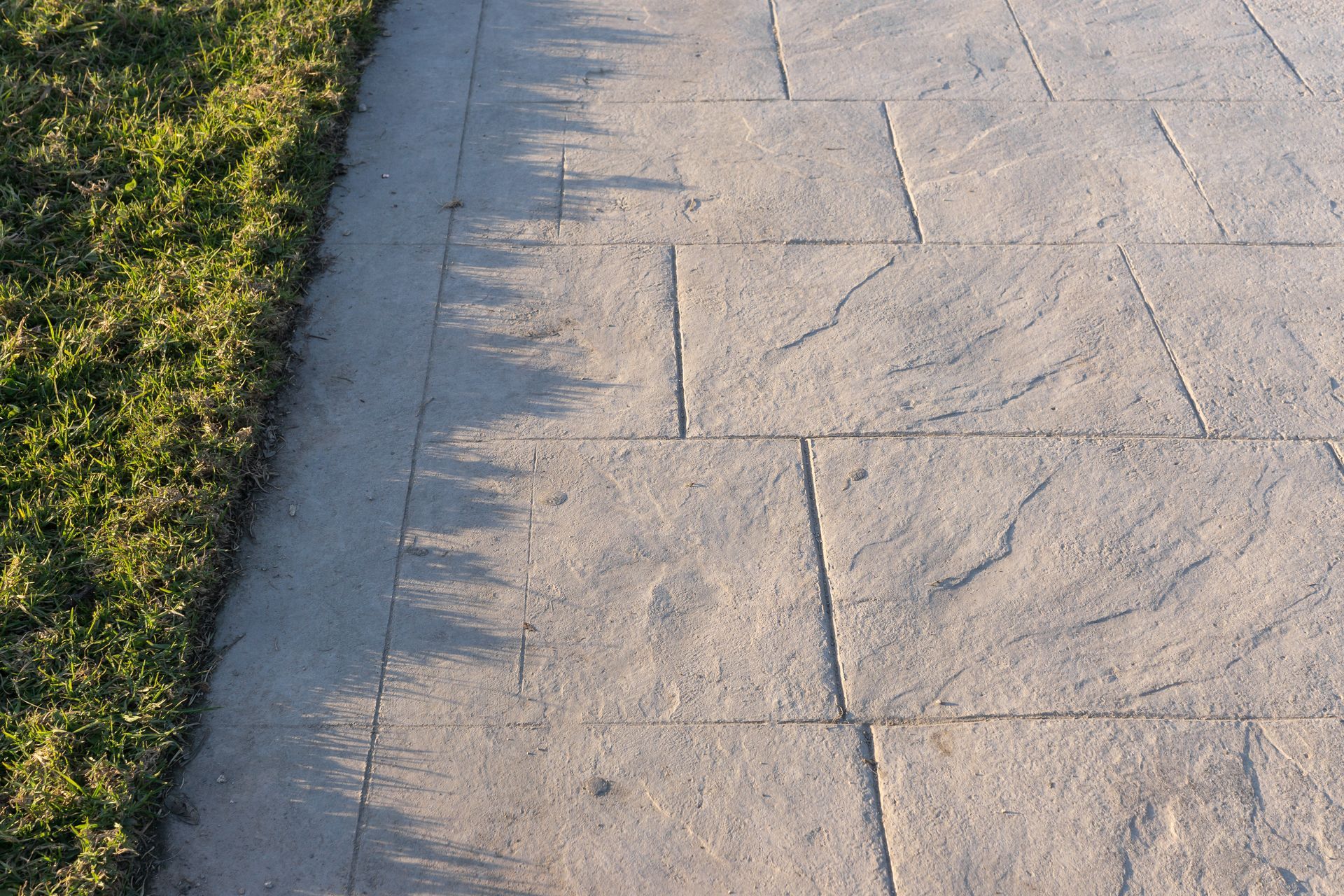 A concrete walkway with grass on the side of it