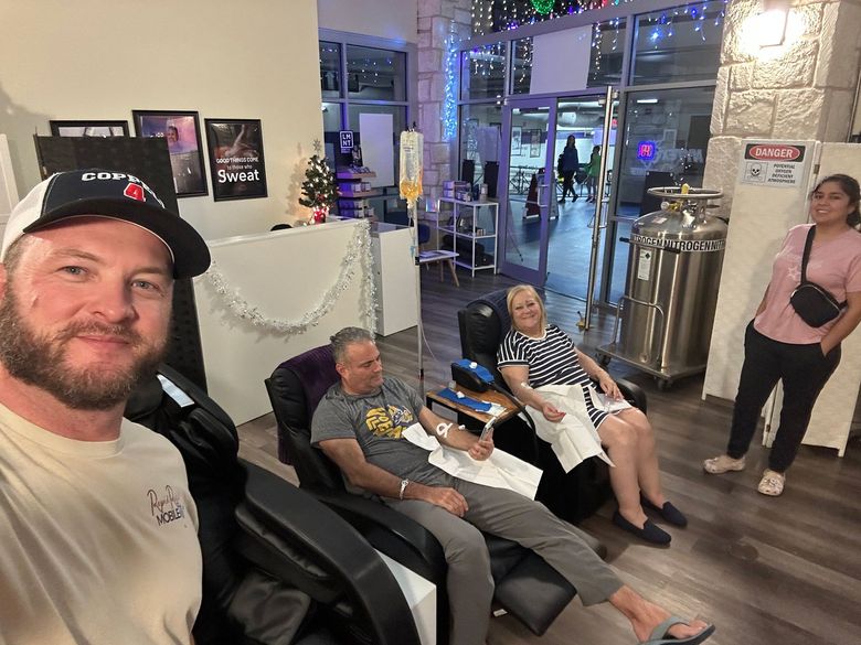 People relaxing in a modern lobby with arcade-style seating and a woman standing nearby
