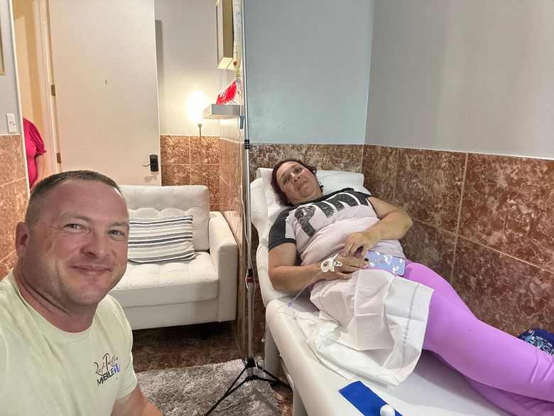 Person reclines in a salon chair with foil in hair as another person smiles in the foreground.