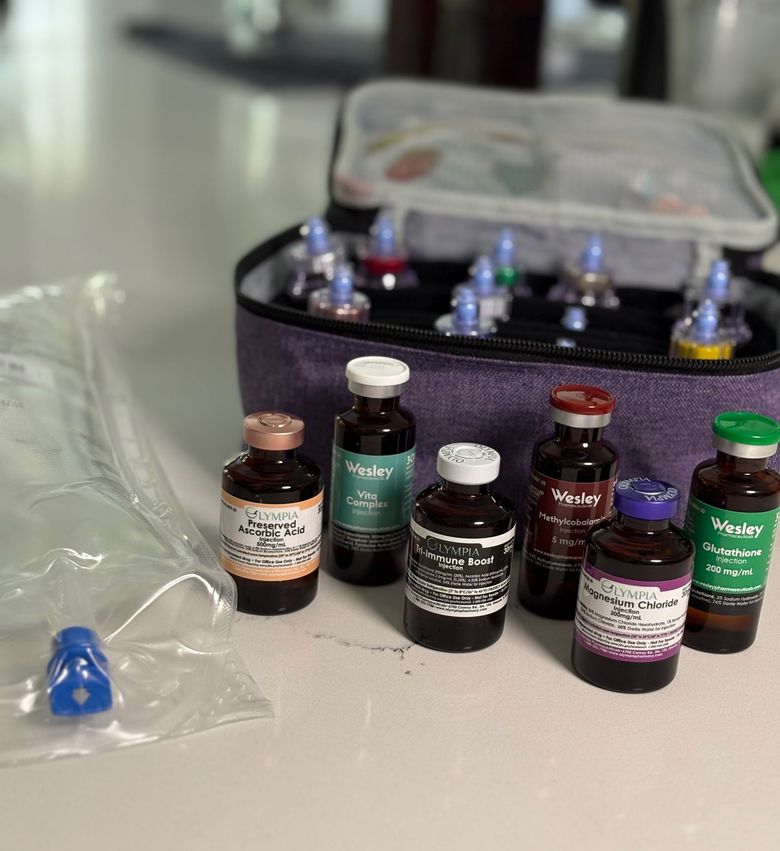 Assorted small medicine vials and bottles in a purple case on a table, with a blue nasal spray bottle nearby