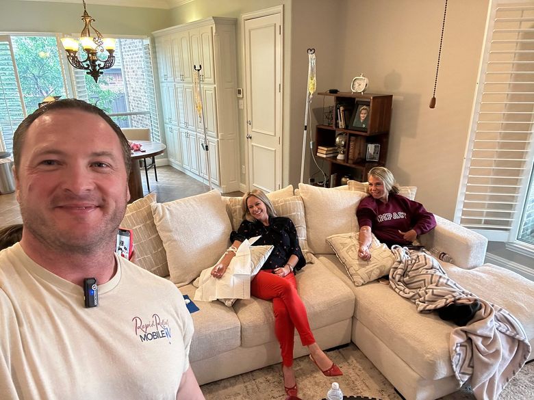 Three people relaxing in a bright living room, with one taking a selfie in the foreground