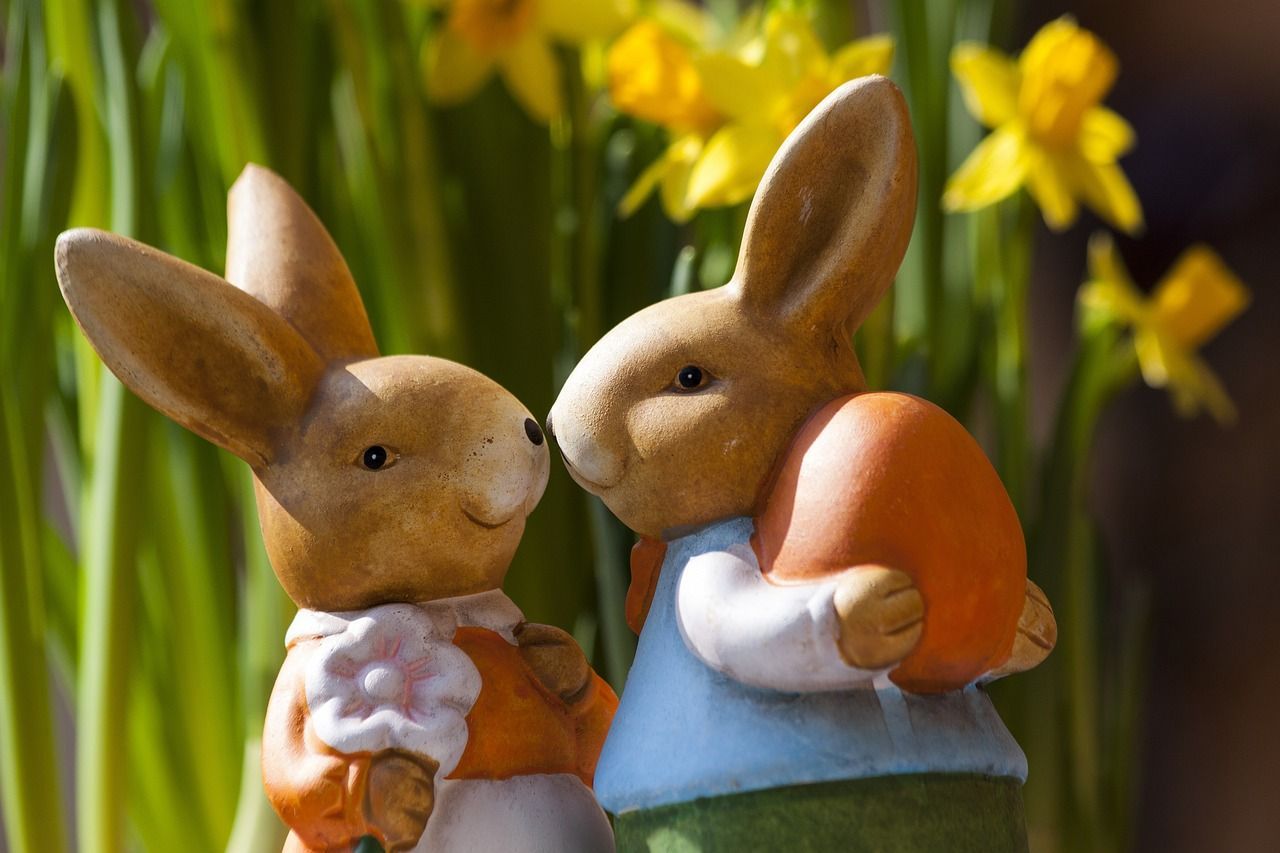 A couple of easter bunnies standing next to each other holding eggs.