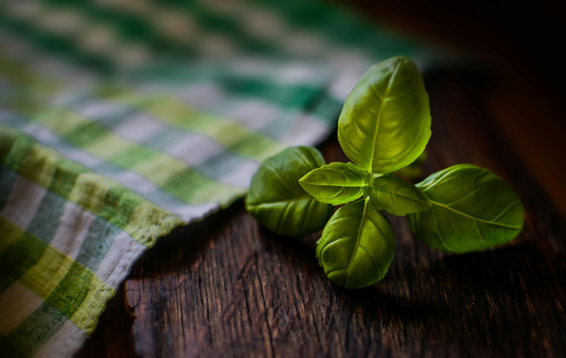 A close up of basil leaves on a wooden table.
