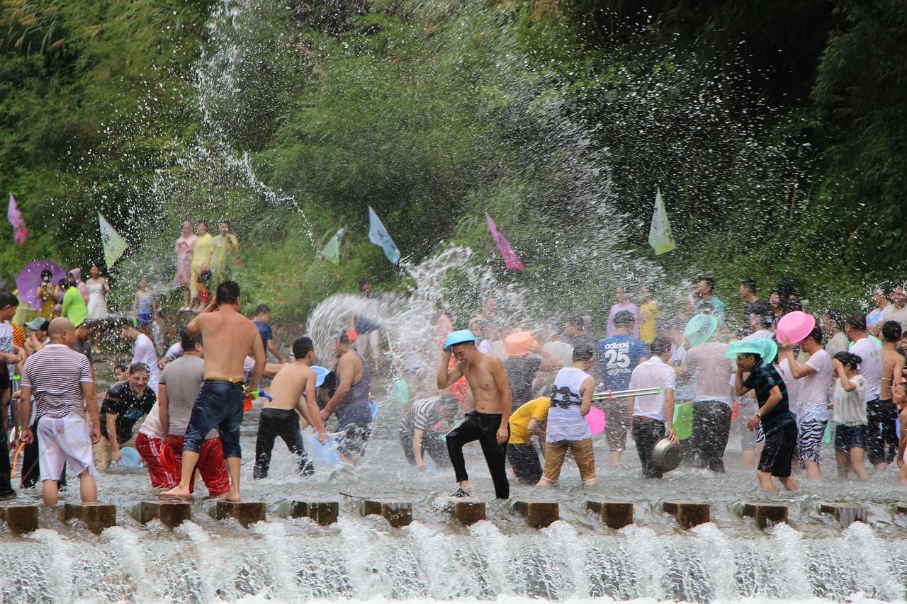 A group of people are standing in front of a waterfall.  Songkran 