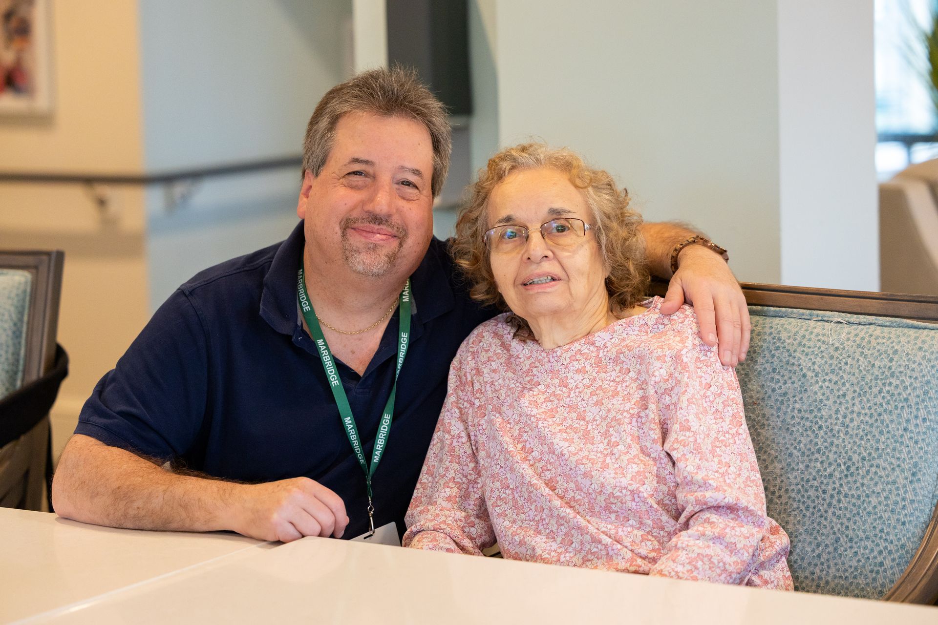 Two people sitting together at a table, smiling in a cozy indoor setting