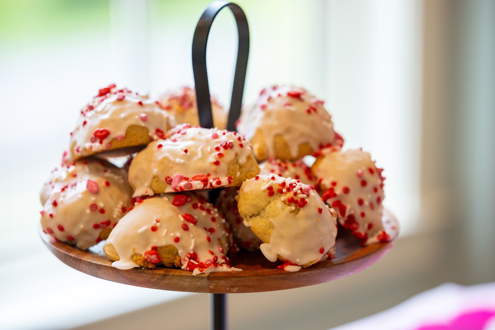 Plate of frosted cookies topped with red sprinkles on a stand