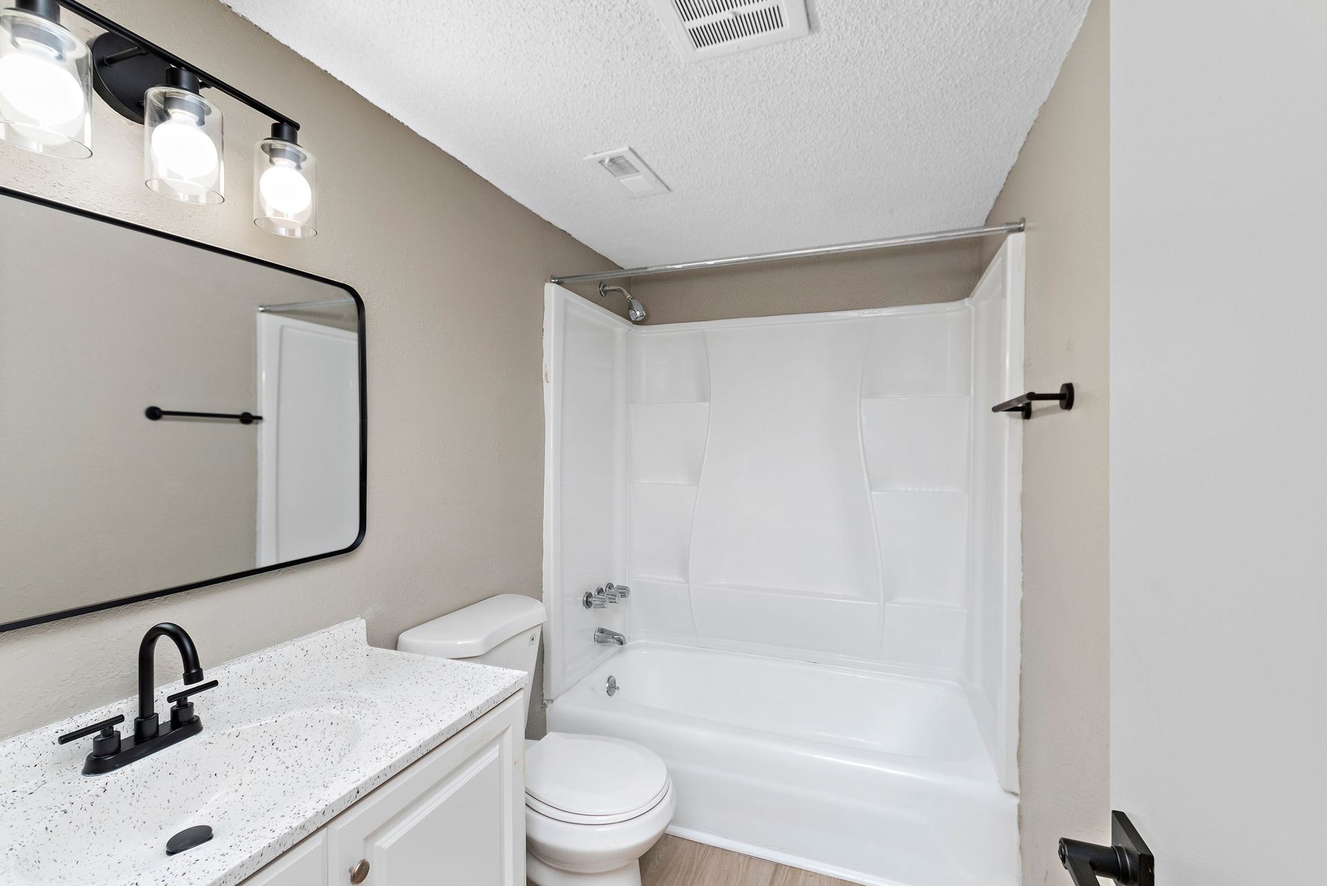 Modern bathroom with white vanity, black fixtures, and a white shower-tub combo
