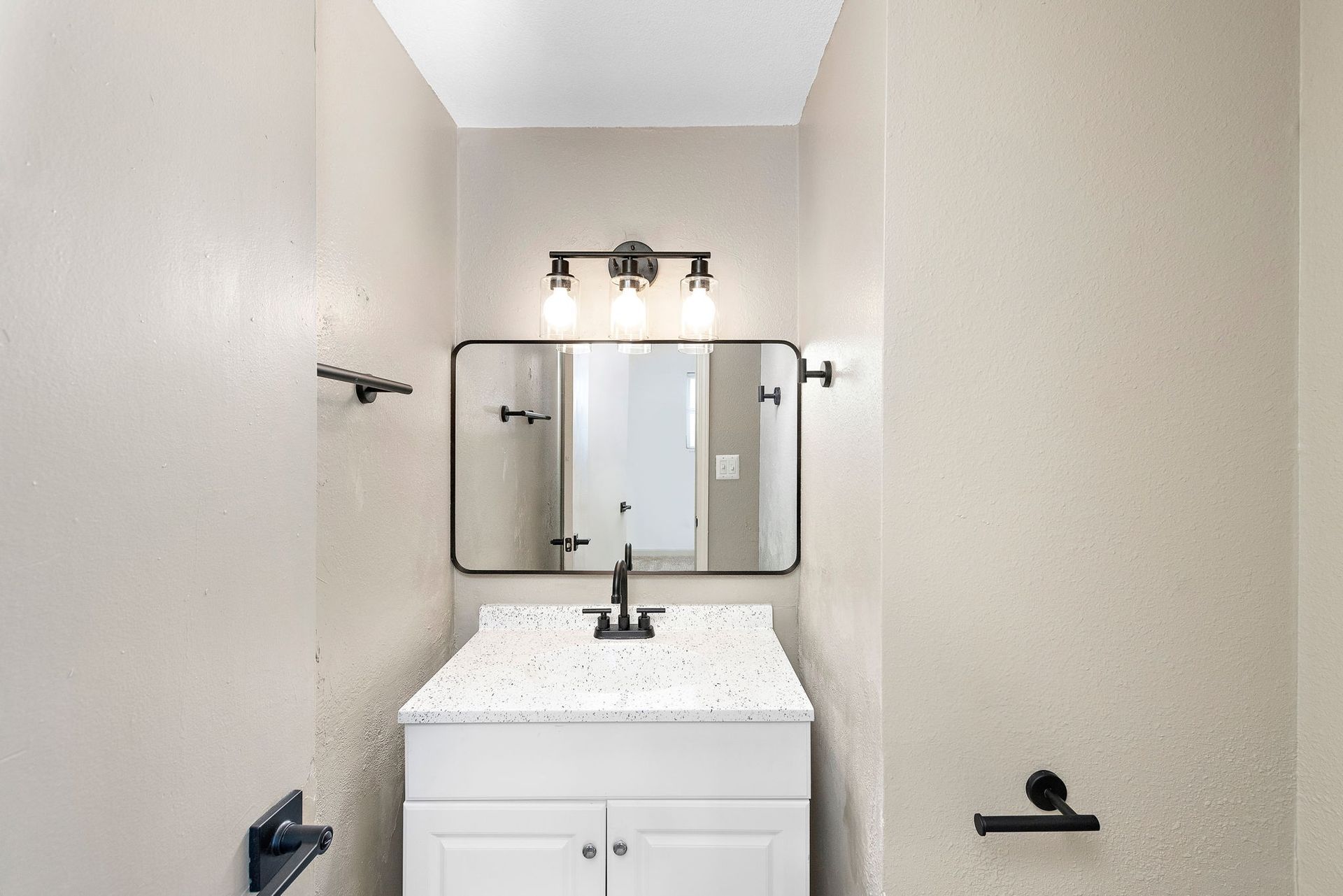 Small bathroom vanity with a mirror, white sink, and beige walls.