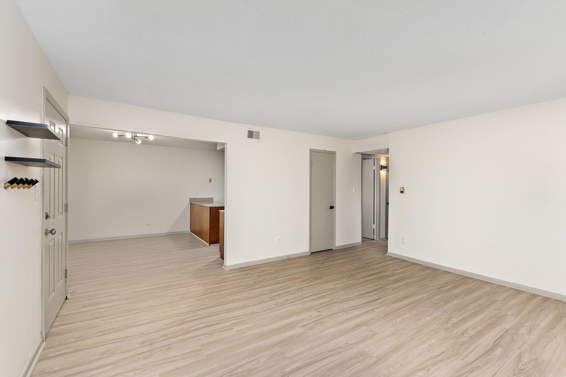 Empty beige living room with open doorway and wood flooring