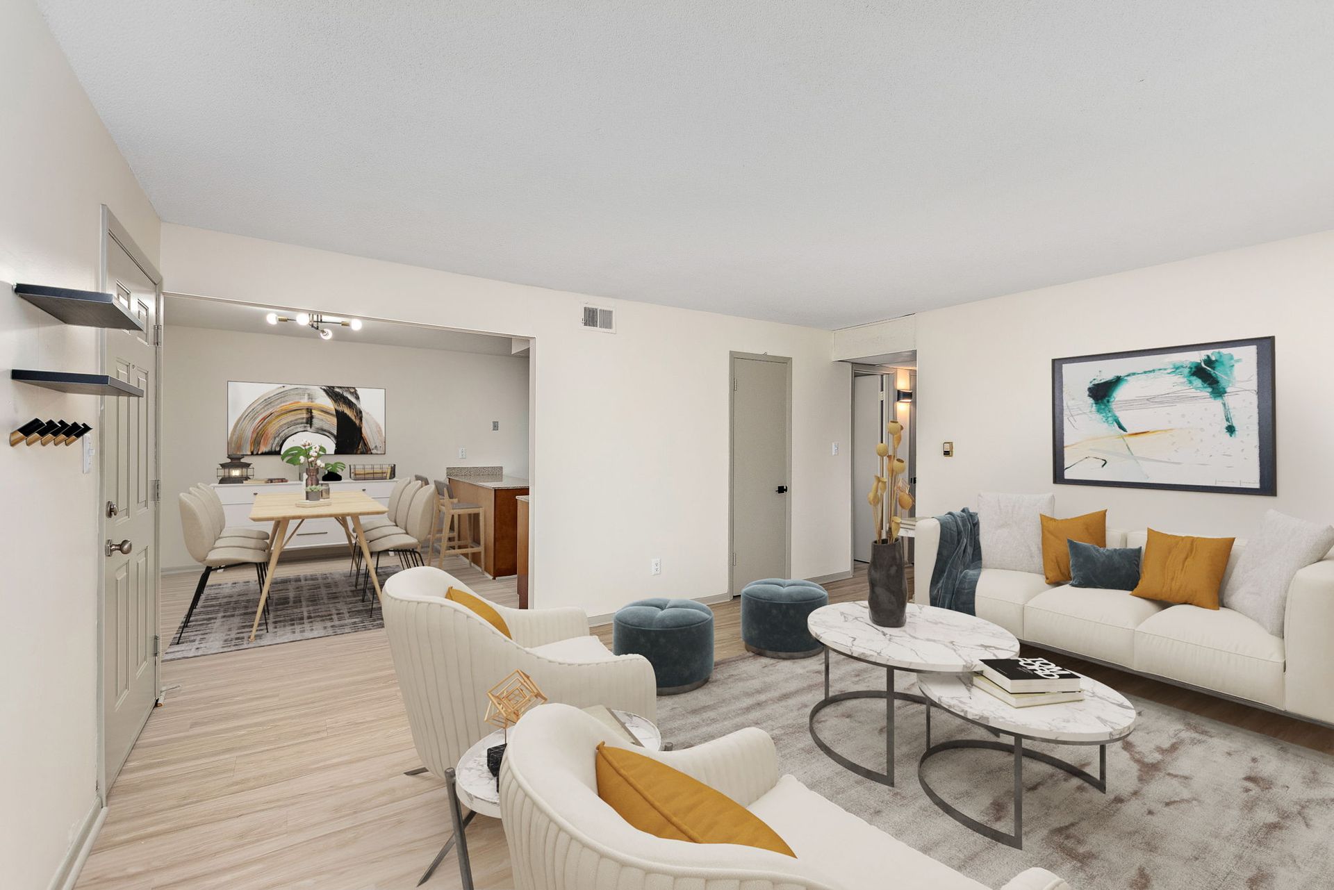Modern living room with white sofas, black coffee table, and open dining area in the background