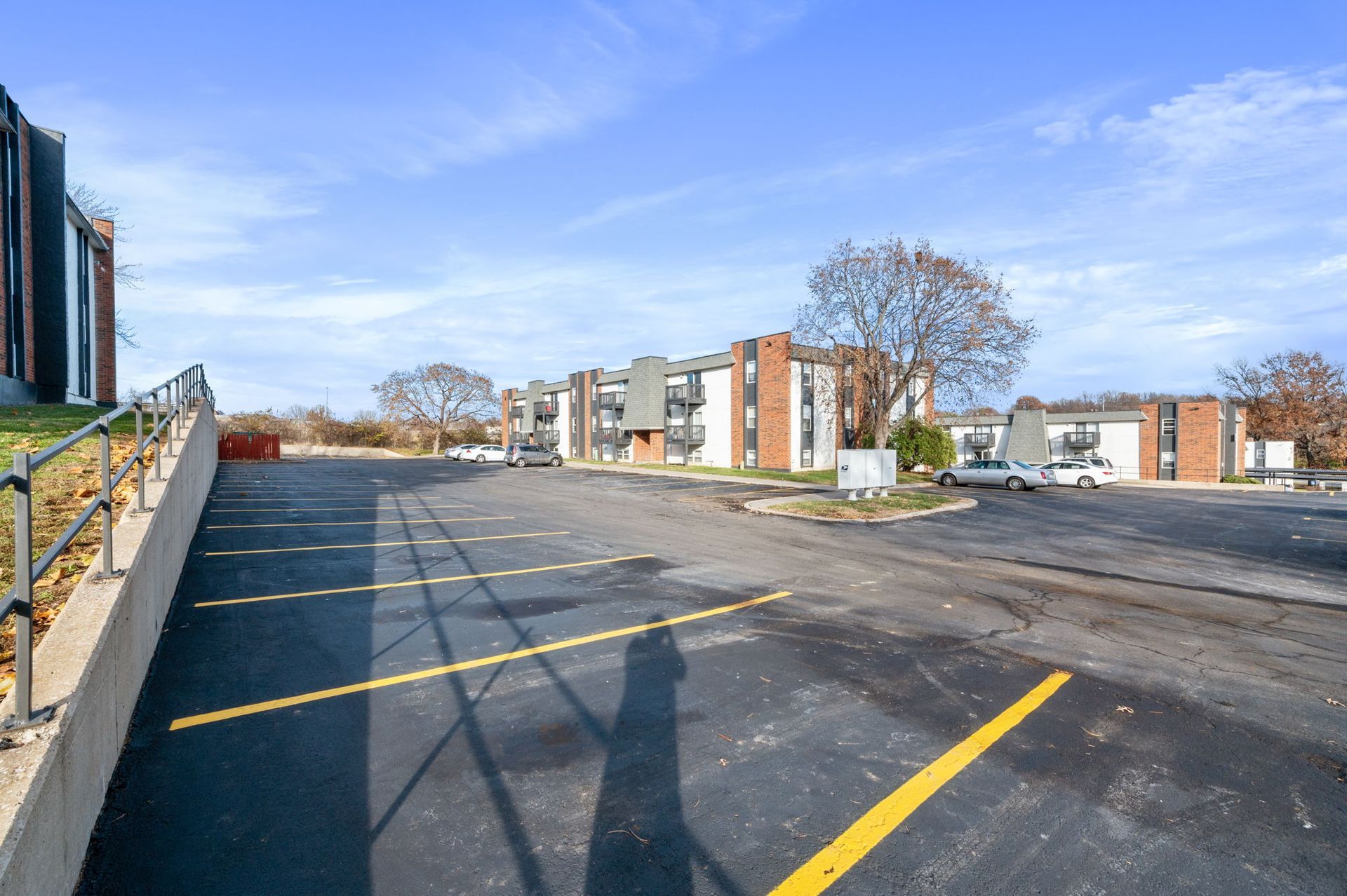 Empty parking lot with yellow lines beside apartment buildings under a clear blue sky