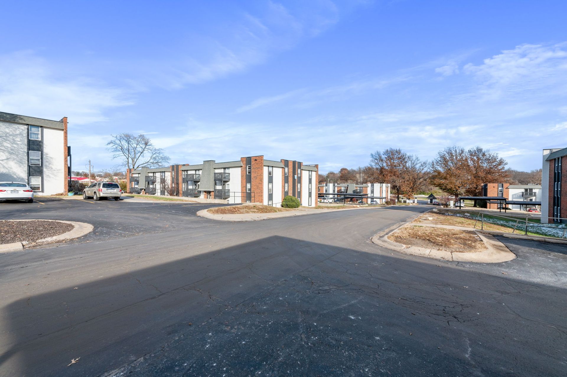 New apartment complex with paved drive, landscaped islands, and blue sky