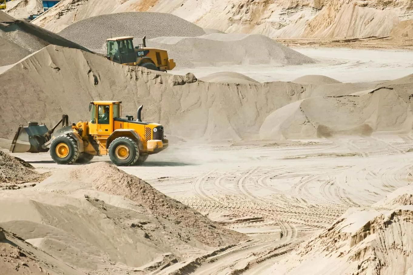 A Yellow Bulldozer Is Driving Through A Pile Of Sand — Dubbo Hardcore Soils & Earthmoving In Dubbo, NSW