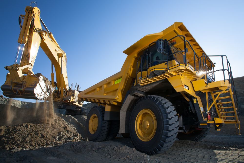 A Yellow Dump Truck Is Being Loaded With Dirt By An Excavator — Dubbo Hardcore Soils & Earthmoving In Dubbo, NSW
