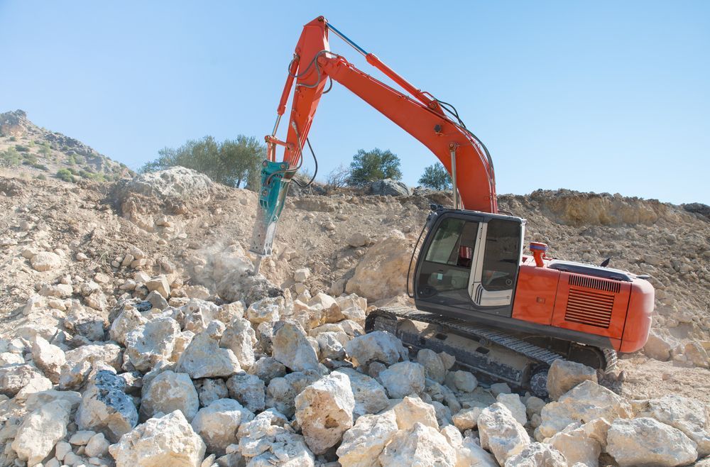 An Excavator Is Working On A Pile Of Rocks In A Quarry — Dubbo Hardcore Soils & Earthmoving In Dubbo, NSW