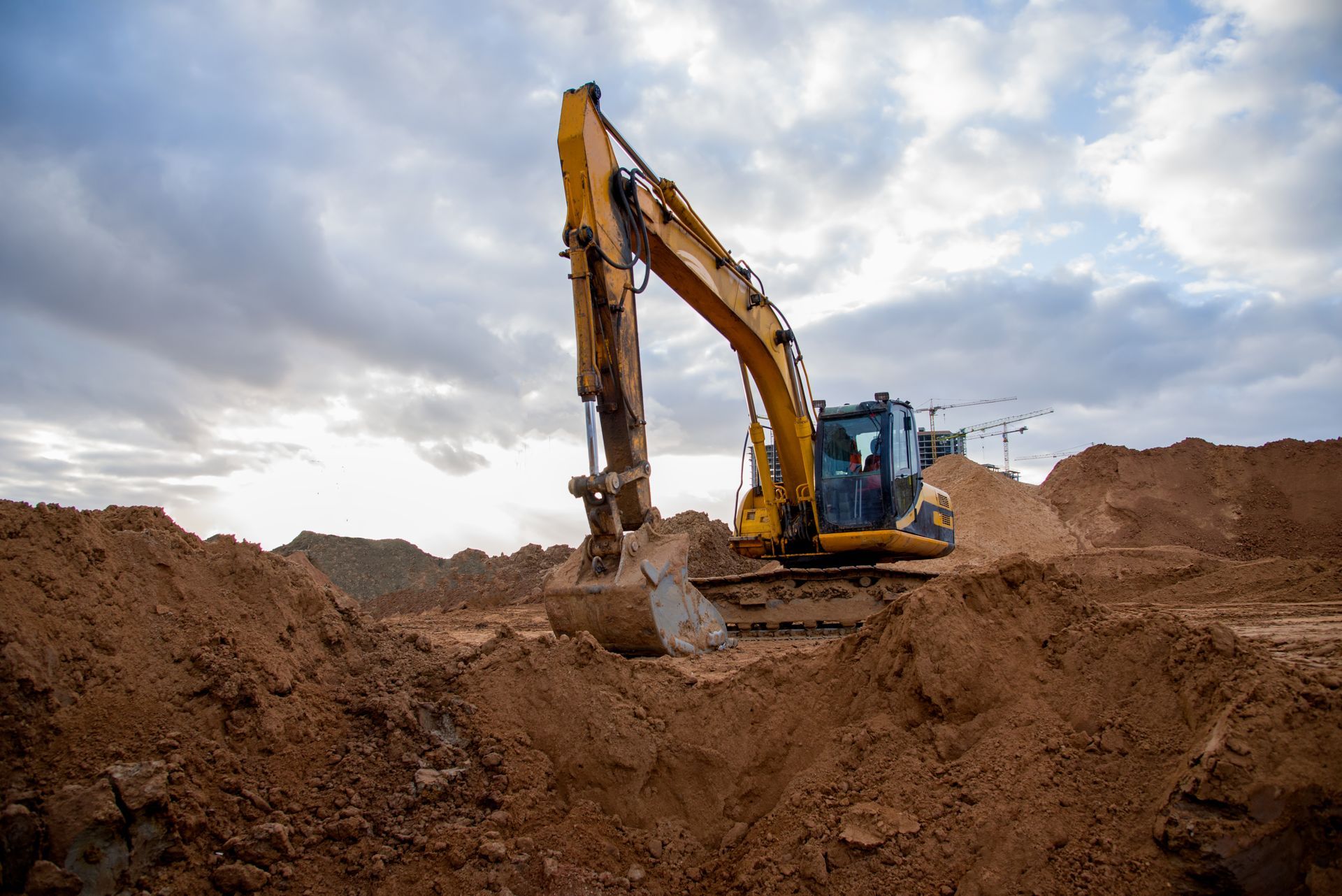 A Yellow Excavator Is Digging A Hole In The Dirt — Dubbo Hardcore Soils & Earthmoving In Dubbo, NSW