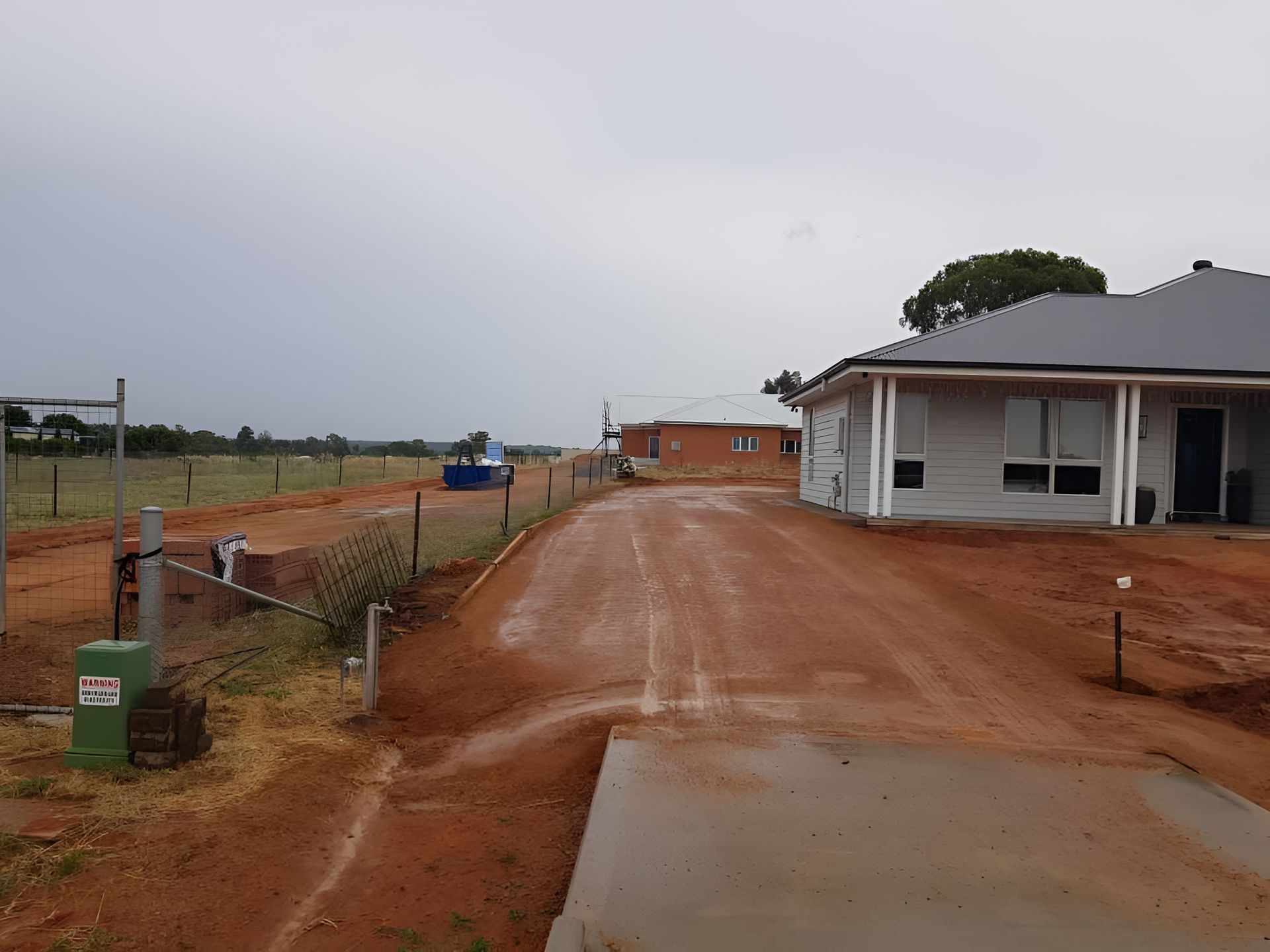 A Dirt Road Leading To A House On A Cloudy Day — Dubbo Hardcore Soils & Earthmoving In Dubbo, NSW