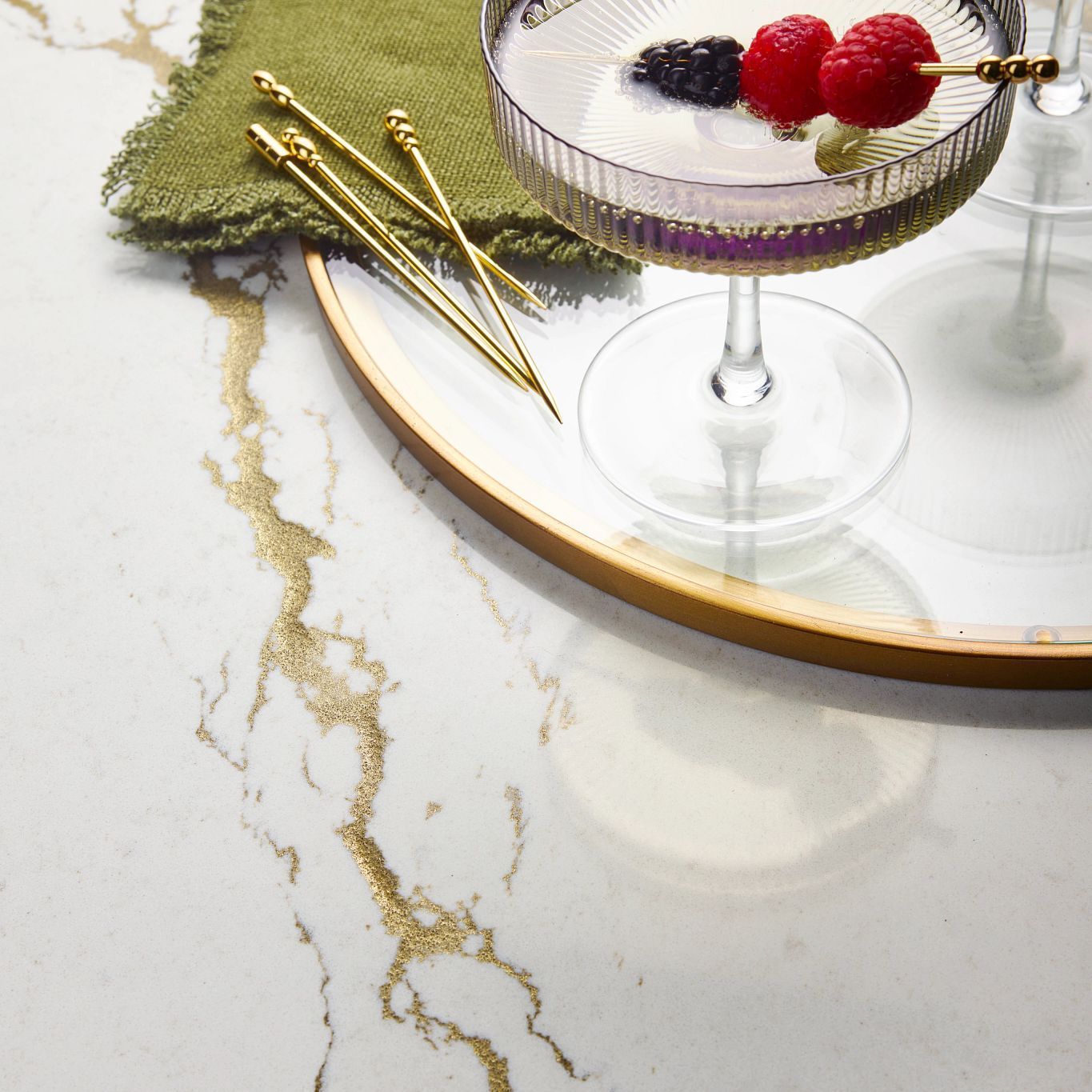 A martini with raspberries on a toothpick in it