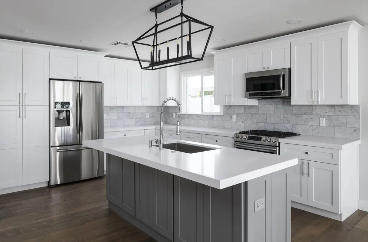 A kitchen with white cabinets , stainless steel appliances , and a large island.