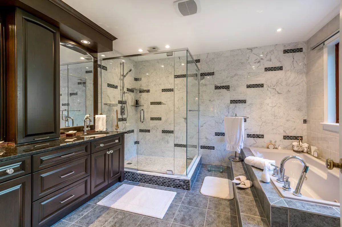 A bathroom with a tub , sink , shower and mirror.