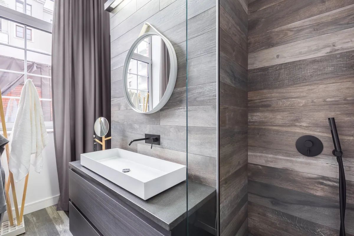 A bathroom with a sink , mirror , and walk in shower.