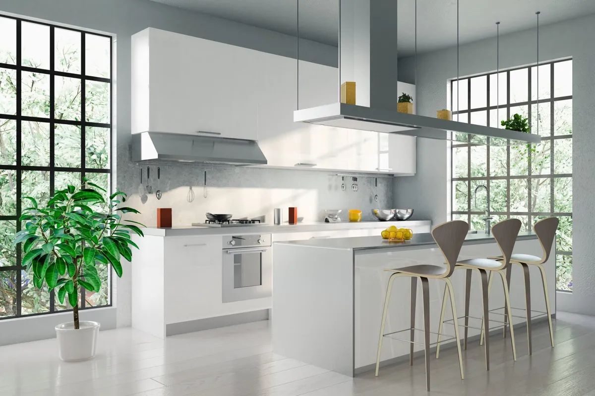 A modern kitchen with white cabinets , stools , and a large island.