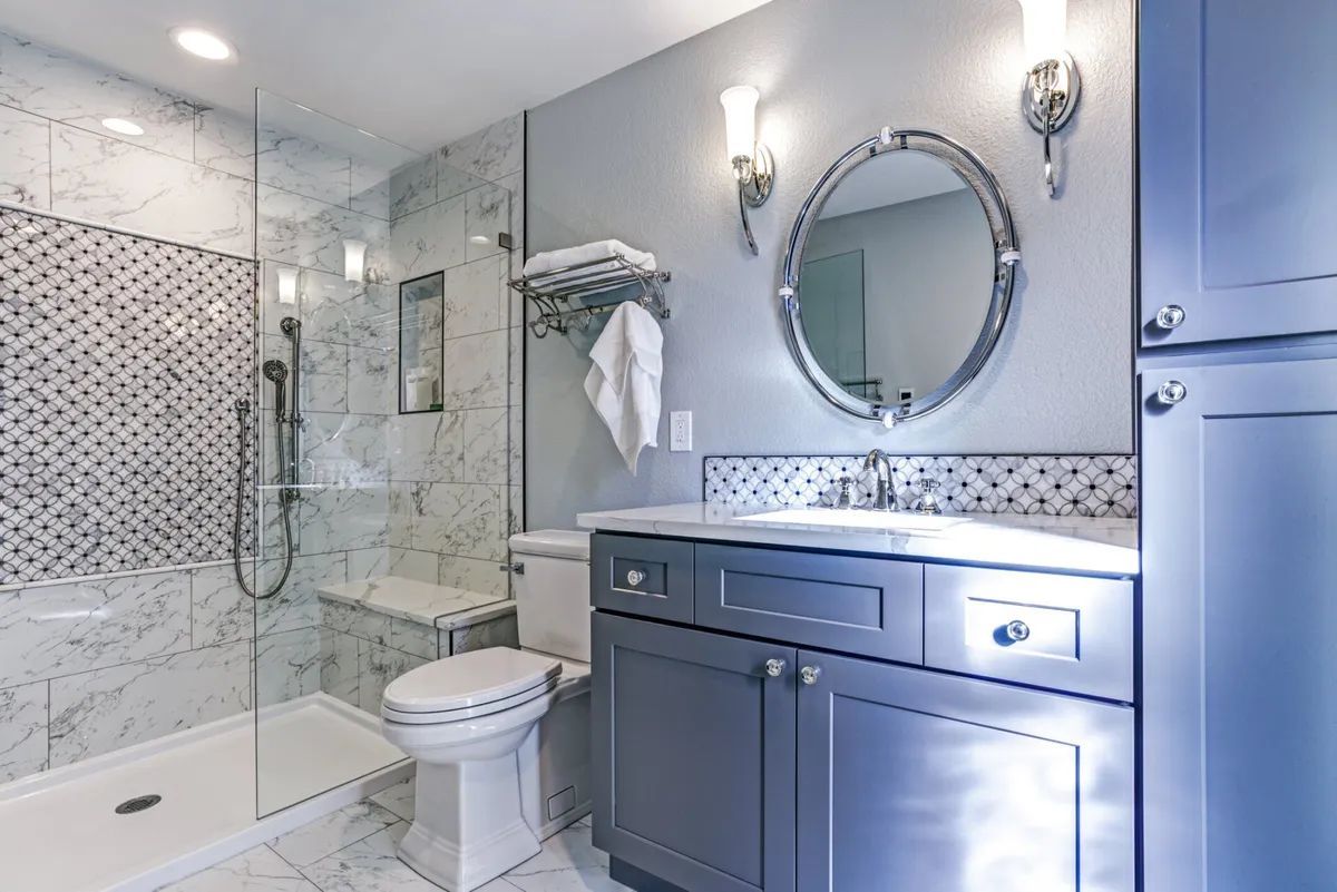 A bathroom with a toilet , sink , mirror and walk in shower.