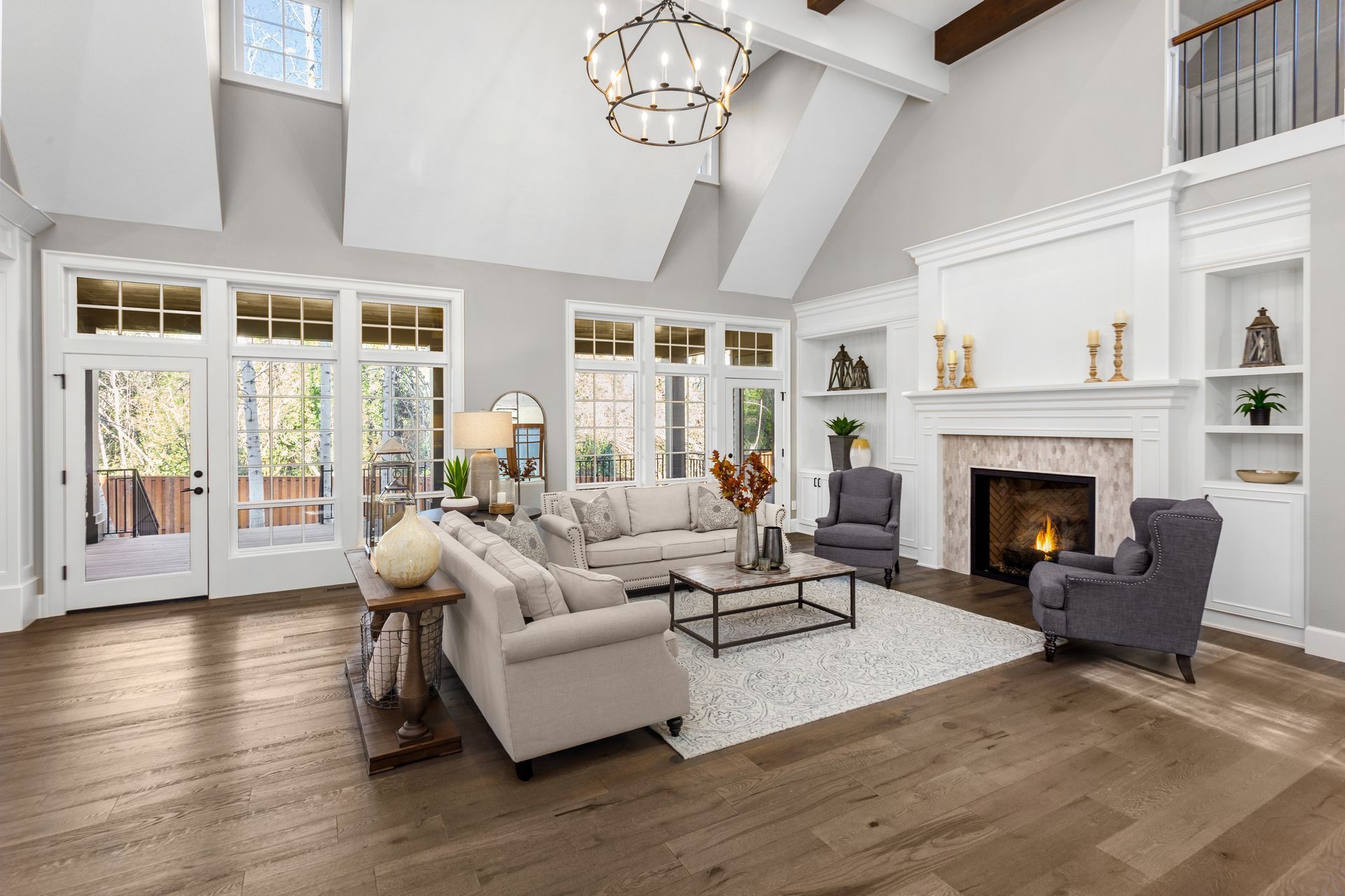 Bright living room with vaulted ceiling, fireplace, gray sectional, and large windows overlooking a patio