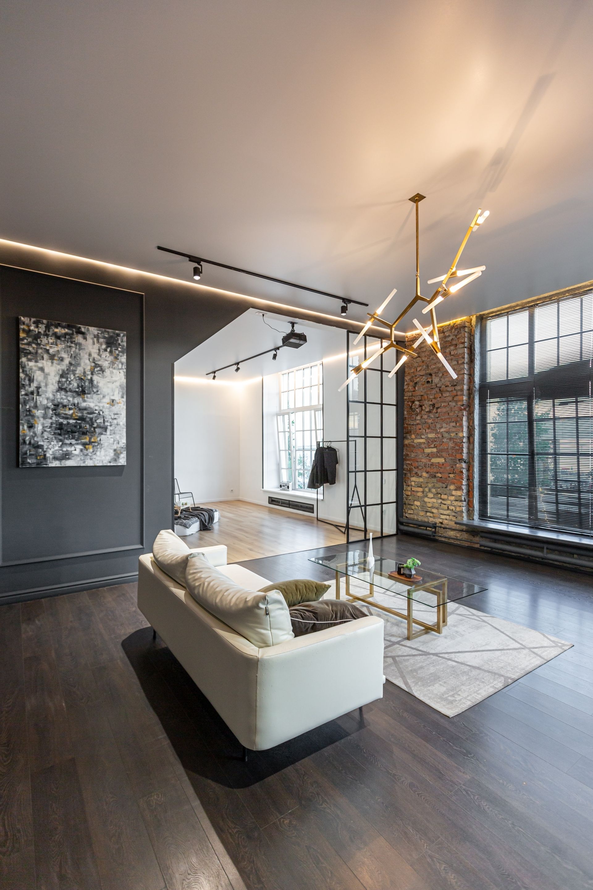Modern living room with white sofa, dark wood floors, tall windows, and a contemporary chandelier