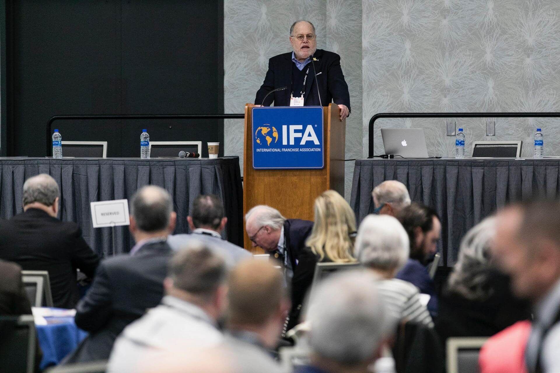 Man speaking at a conference behind a podium with