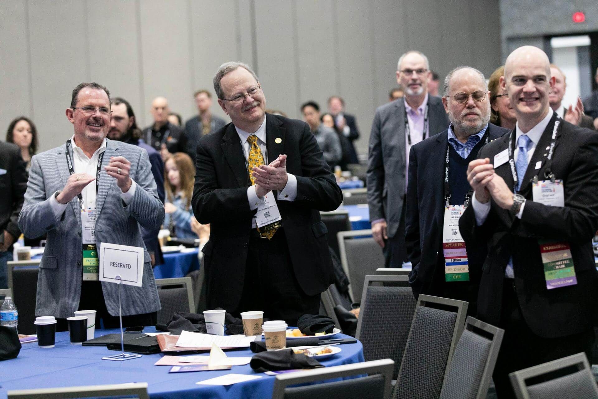 A conference room filled with people seated at tables and praying.