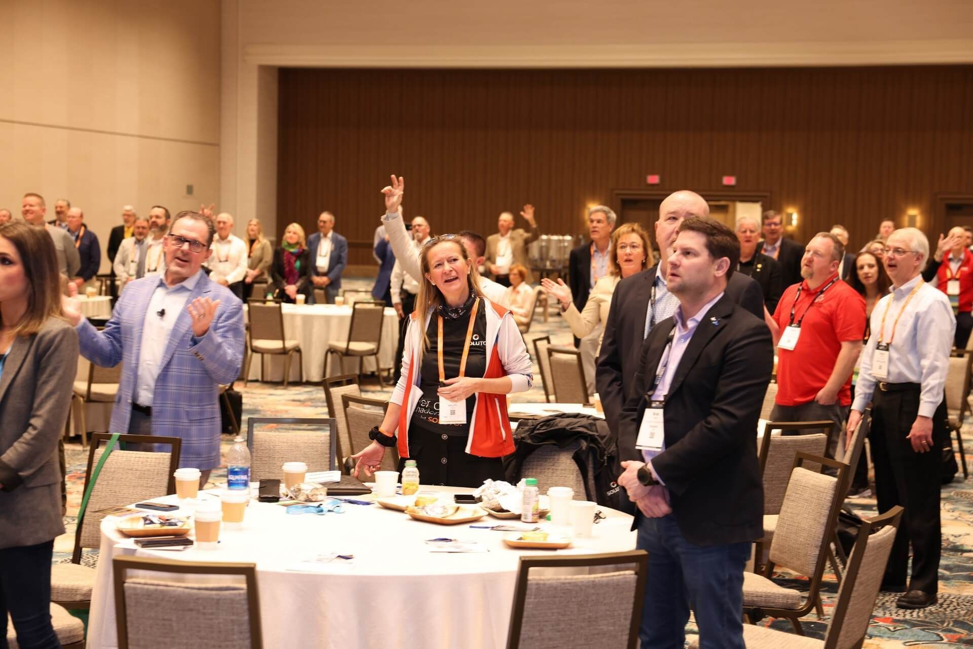 Group of people in a conference room, some with arms raised, celebrating.