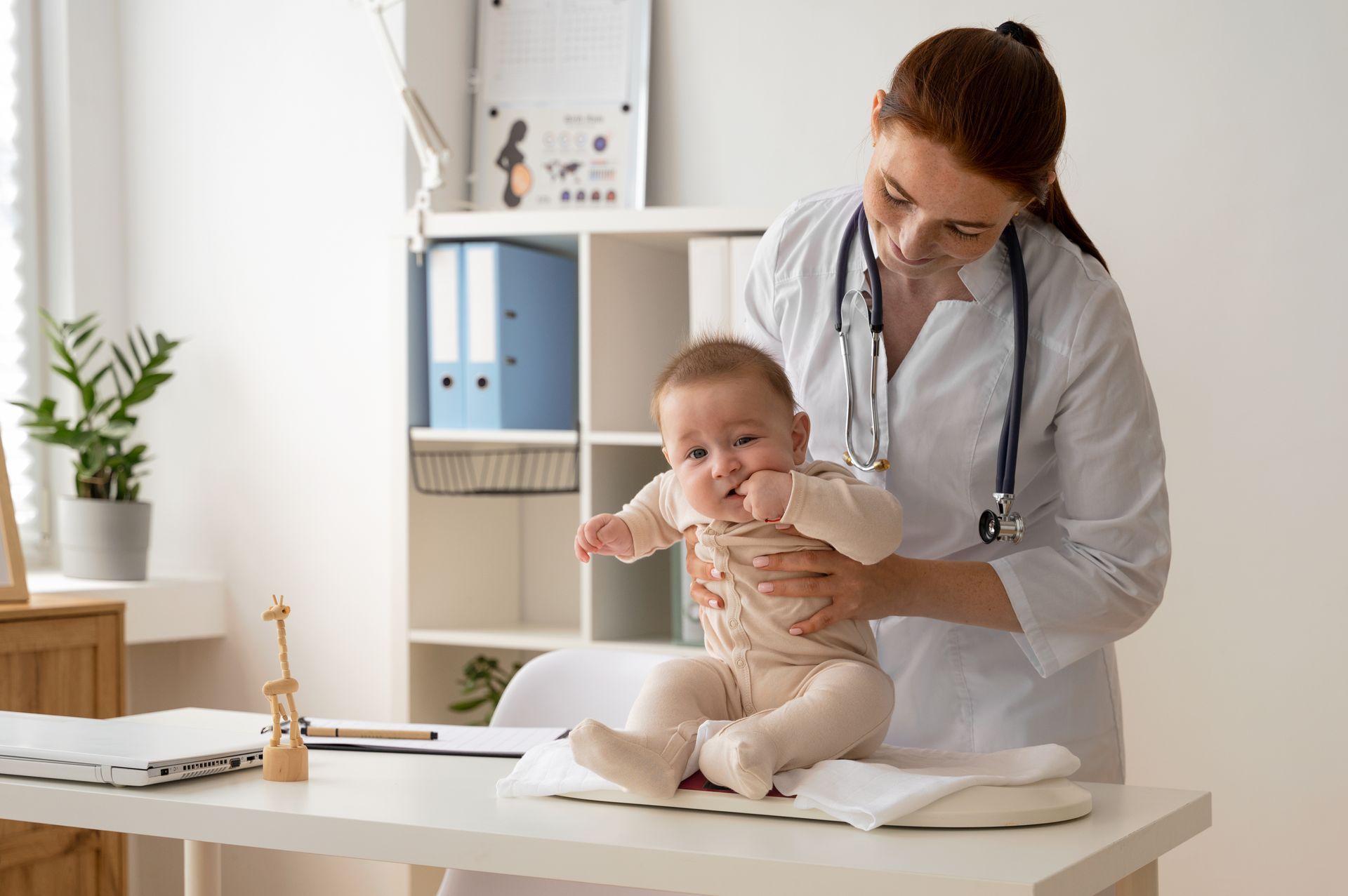 Médico examinando um bebê em um consultório bem iluminado, com o bebê sentado em uma mesa.