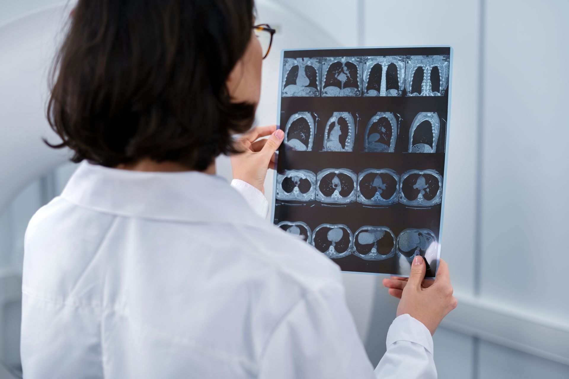 Médico examinando filme de tomografia cerebral em um consultório médico bem iluminado.