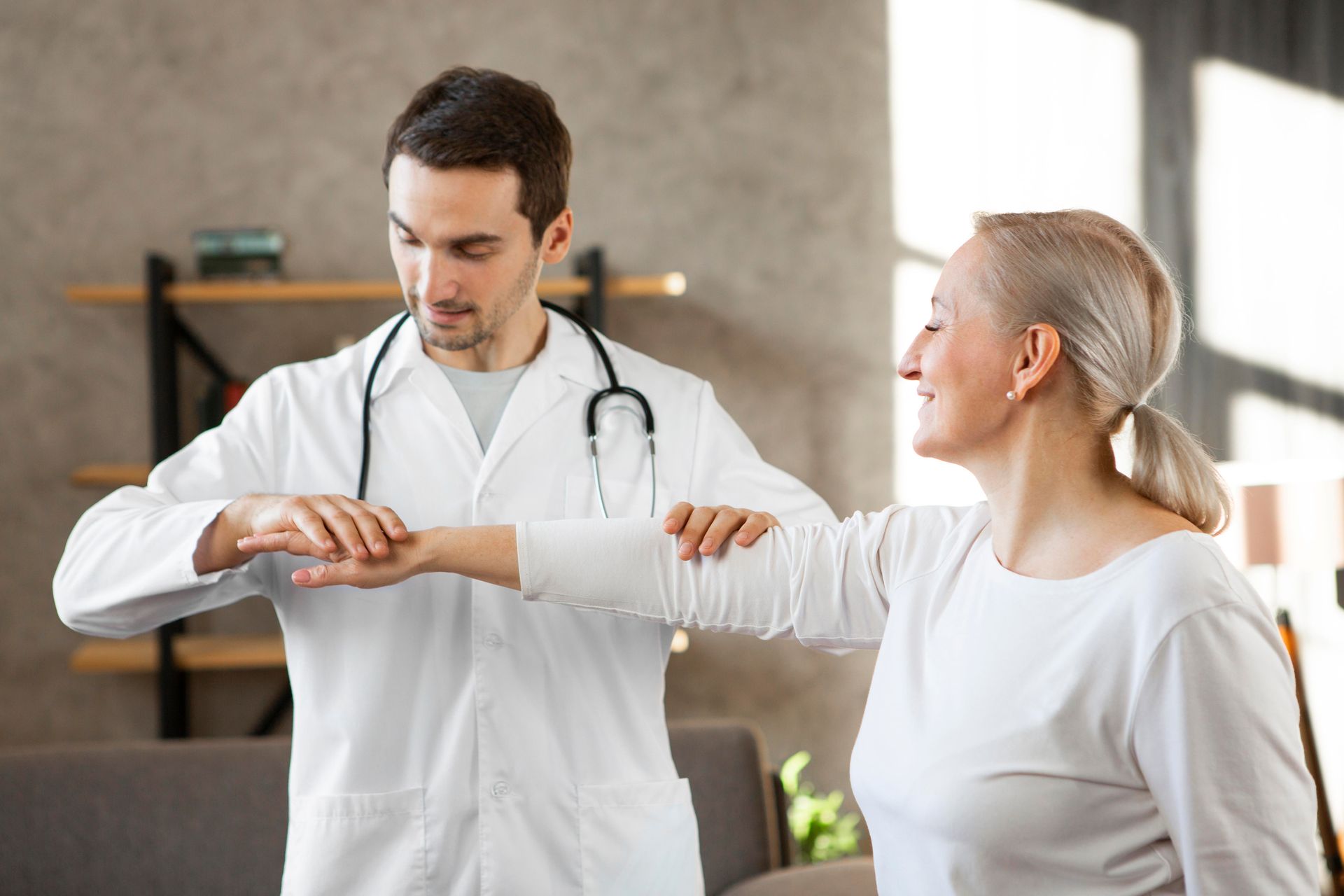Médico examinando o pulso de um paciente em uma clínica bem iluminada, ambos vestindo blusas brancas e sorrindo.