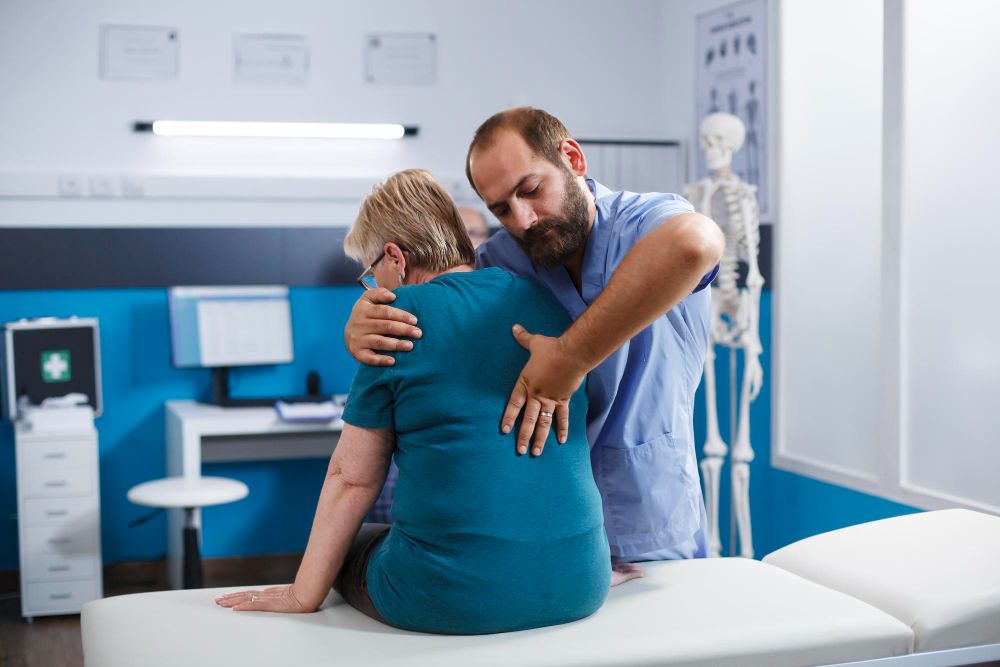 Médico confortando paciente sentado em uma sala de exames médicos.