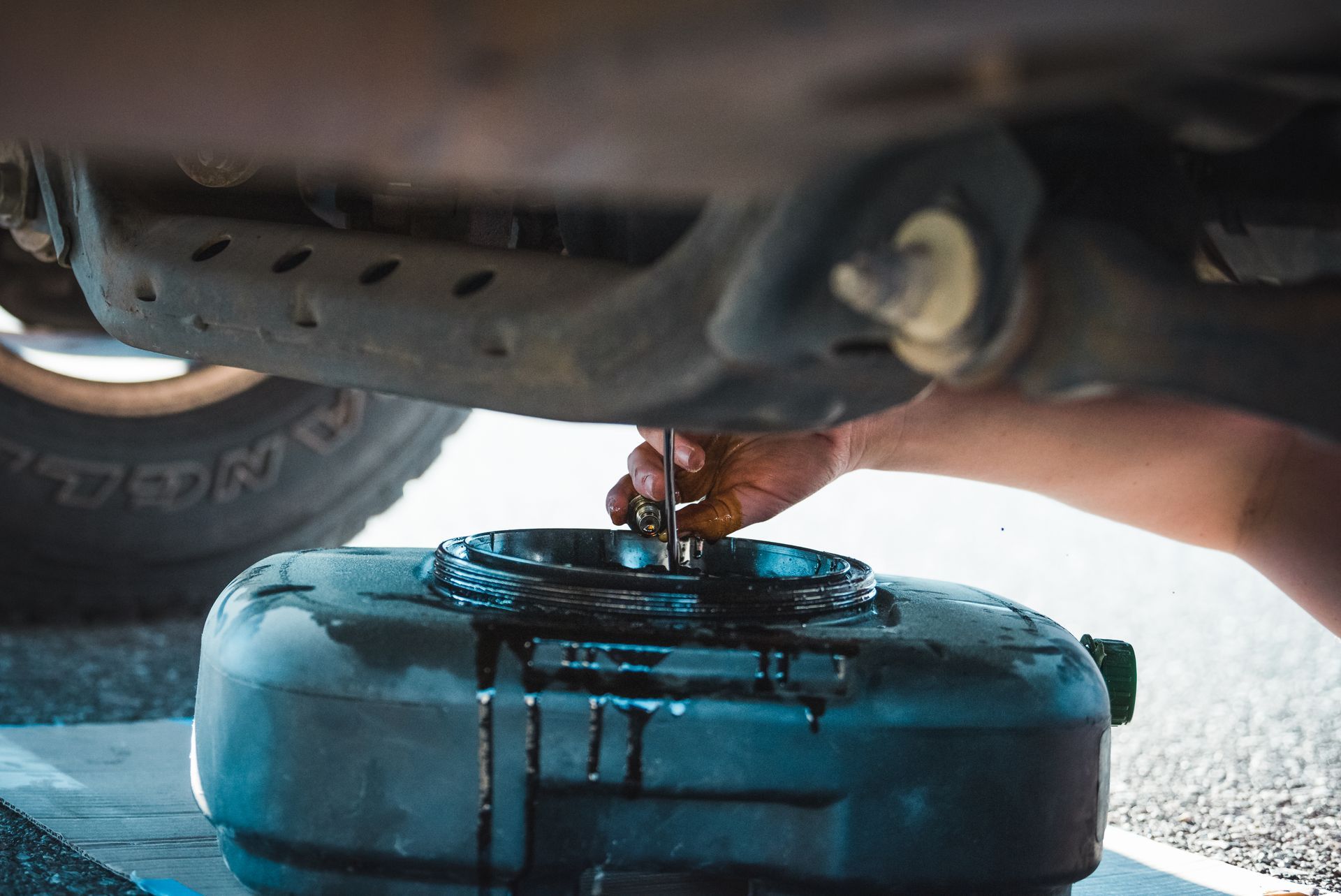 Oil draining from a vehicle into a blue container during an oil change
