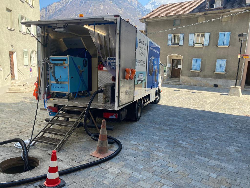 Un camion est garé devant un bâtiment avec un tuyau attaché dessus.