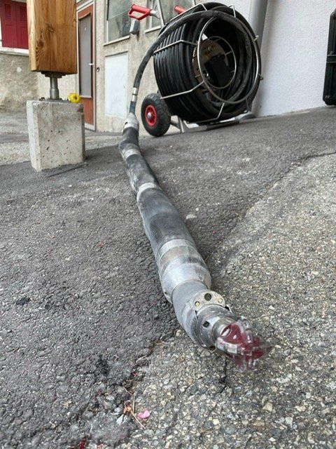 Un tuyau est posé sur le sol à côté d'un rouleau de câble