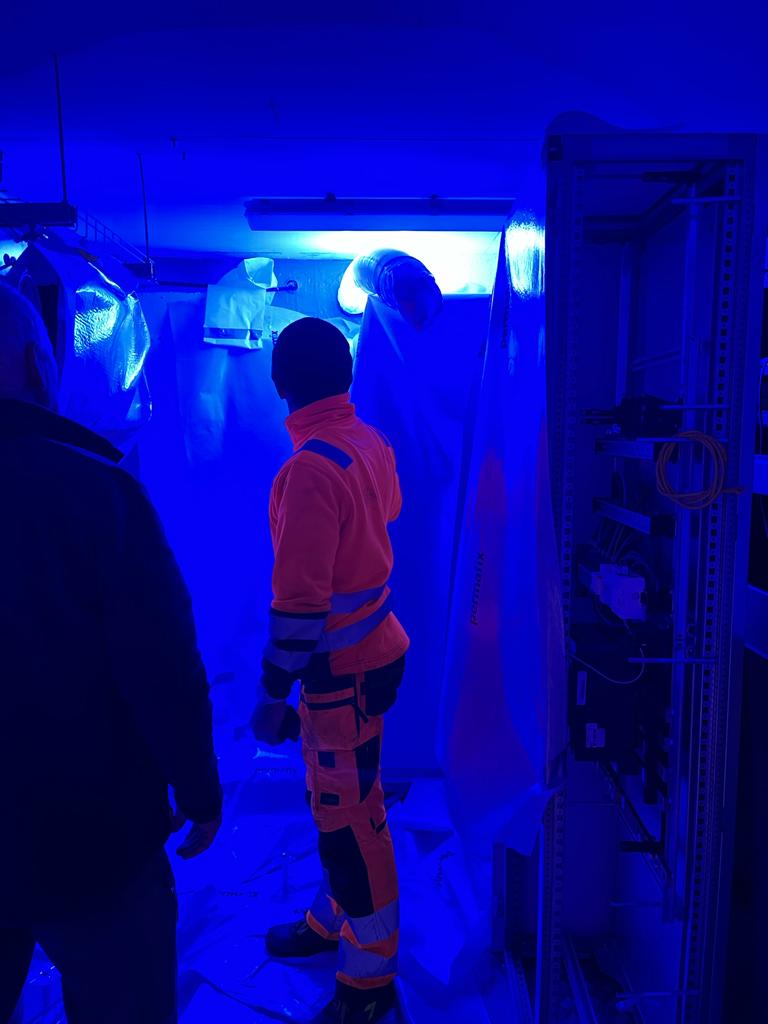 Un groupe de personnes se tient dans une pièce avec des lumières bleues.