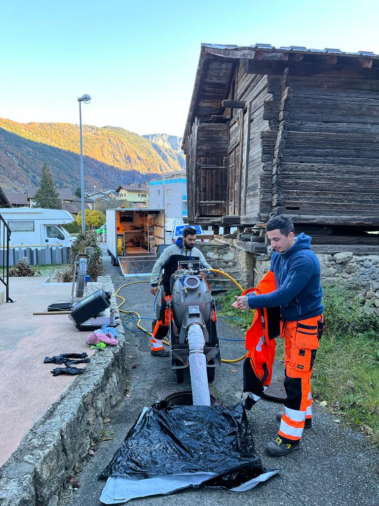 Un groupe d'hommes travaille sur un tuyau devant un bâtiment en bois.
