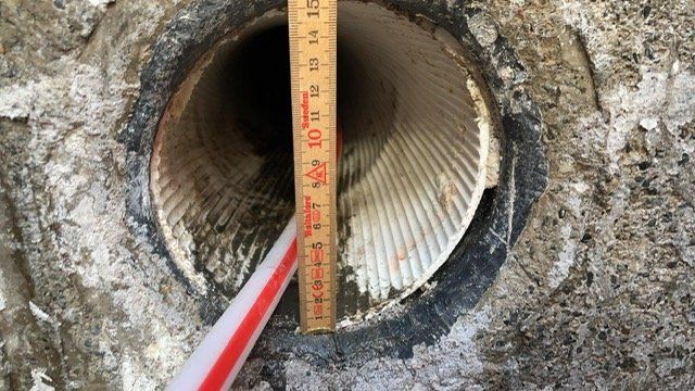 Une règle en bois est utilisée pour mesurer le diamètre d'un tuyau.