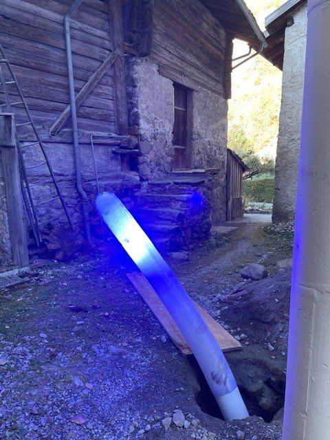 Une lumière bleue brille sur un tuyau devant un bâtiment.