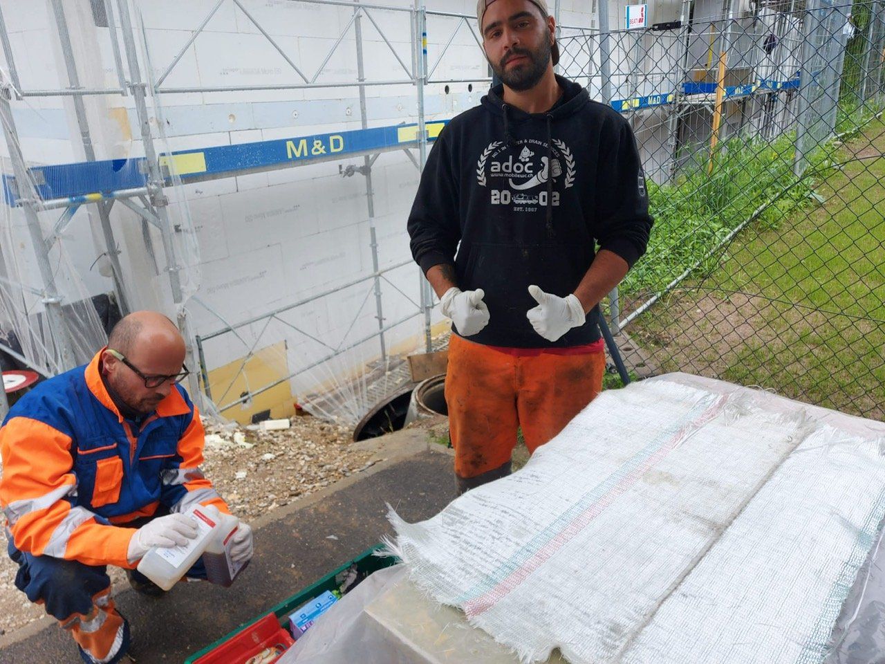 Deux hommes se tiennent l'un à côté de l'autre devant un bâtiment sur lequel est écrit mao
