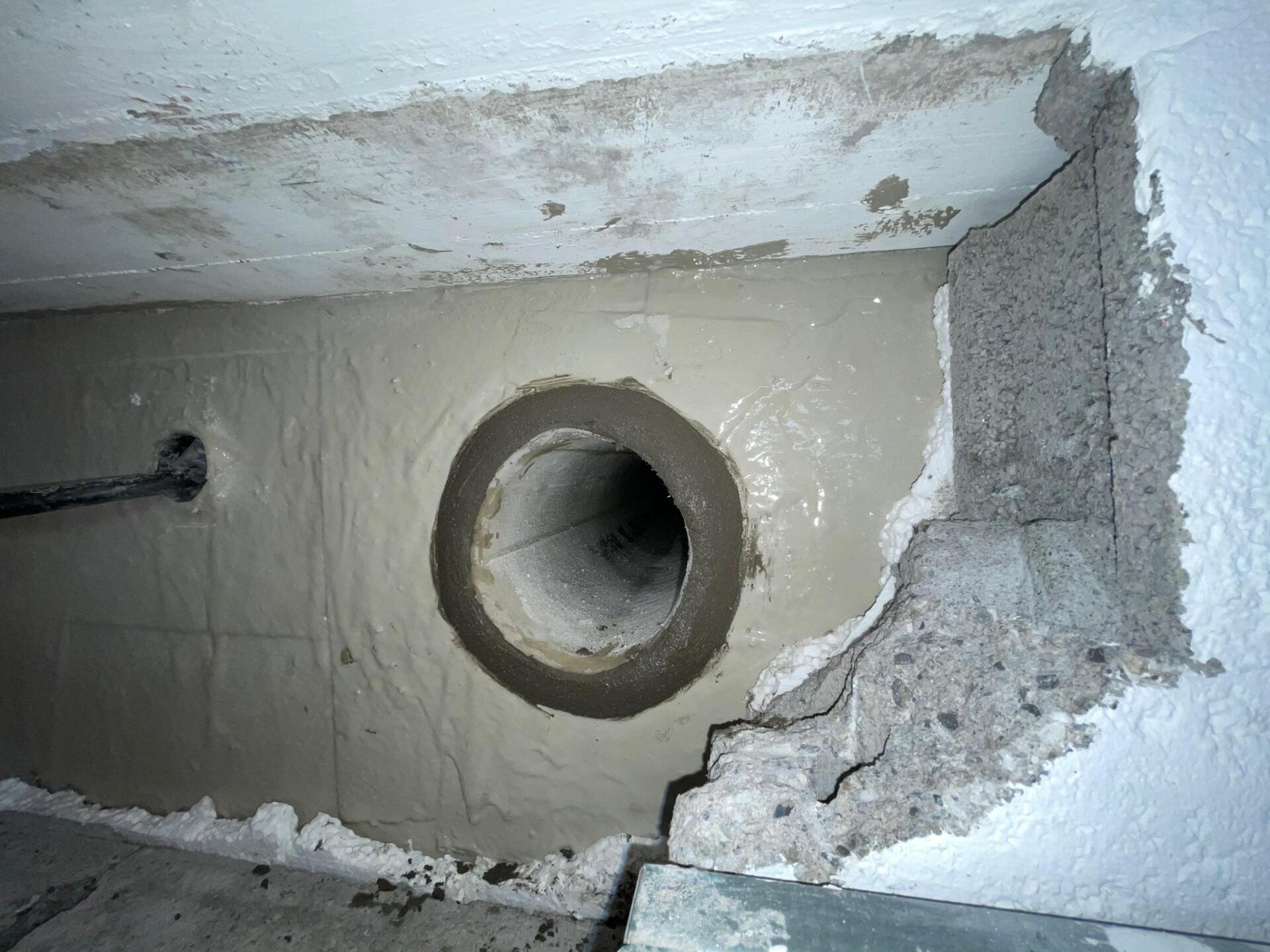 Un trou dans un mur avec un tuyau qui en sort.