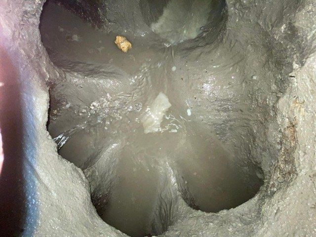 Un gros plan d'un trou dans le sol avec de l'eau qui en sort.