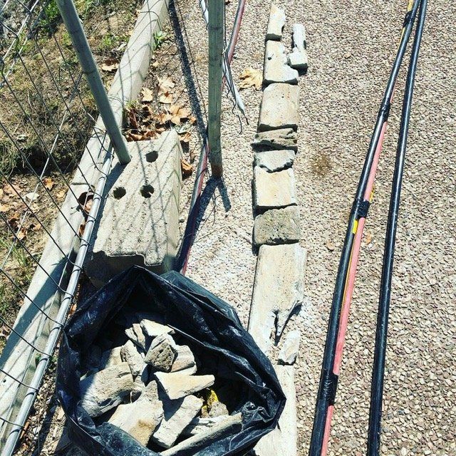 Un sac de pierres repose sur le sol à côté d'une clôture