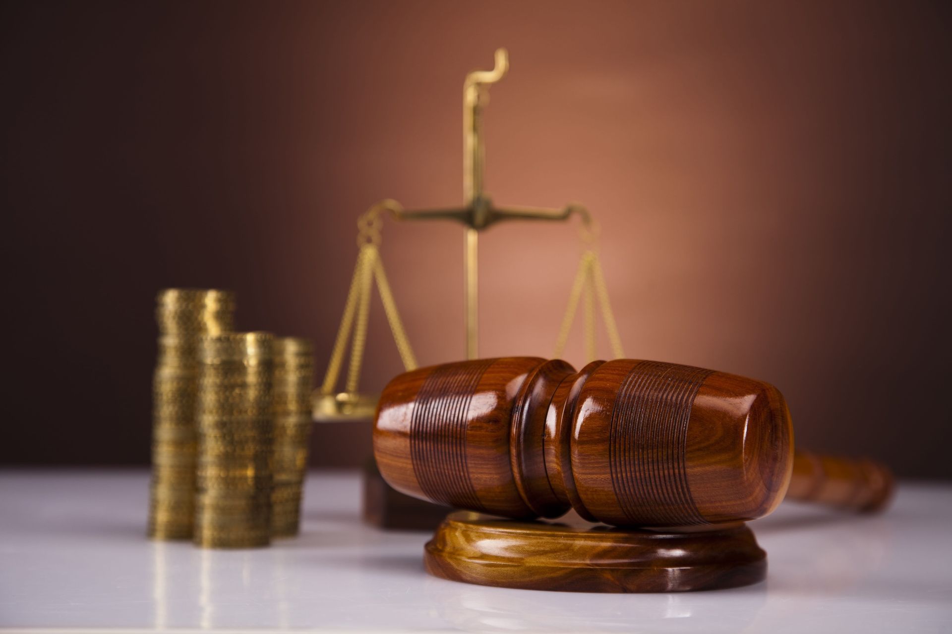 Gavel, scales of justice, and stacked coins on a table, symbolizing law and financial judgment