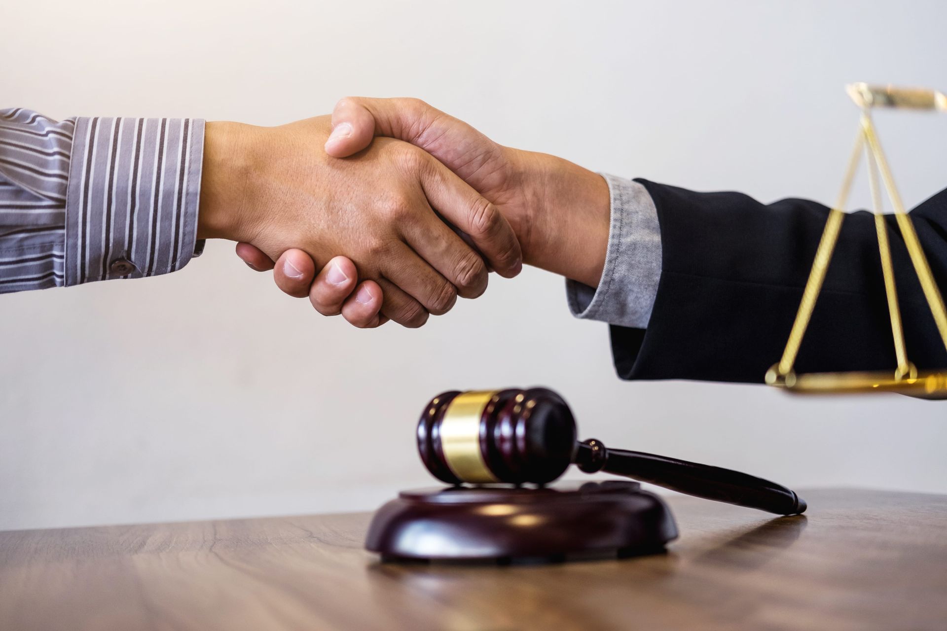 Handshake over gavel and scales symbolizing legal agreement